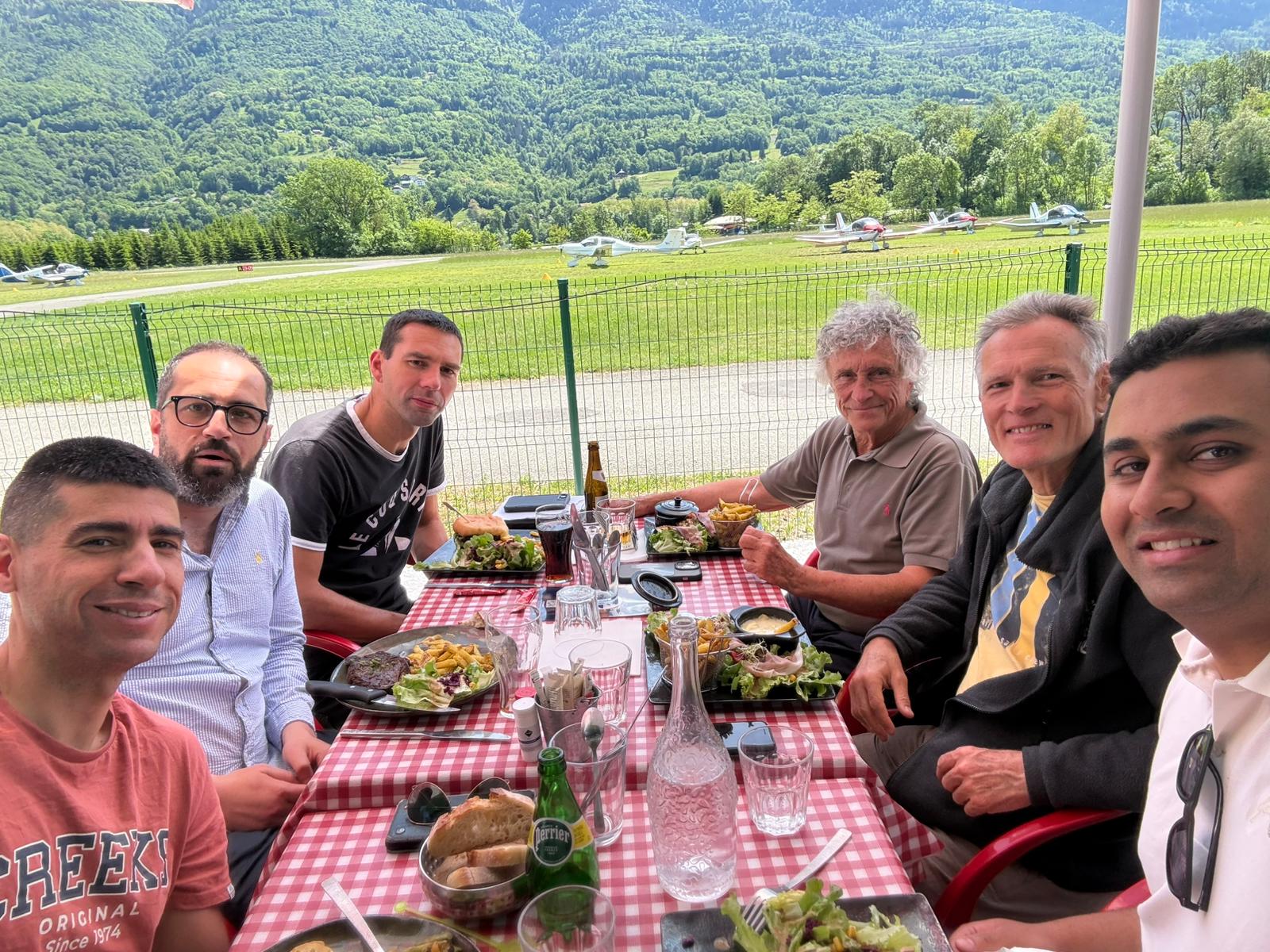 L'équipage du voyage Montagne attablé en terrasse, montagnes en fond
